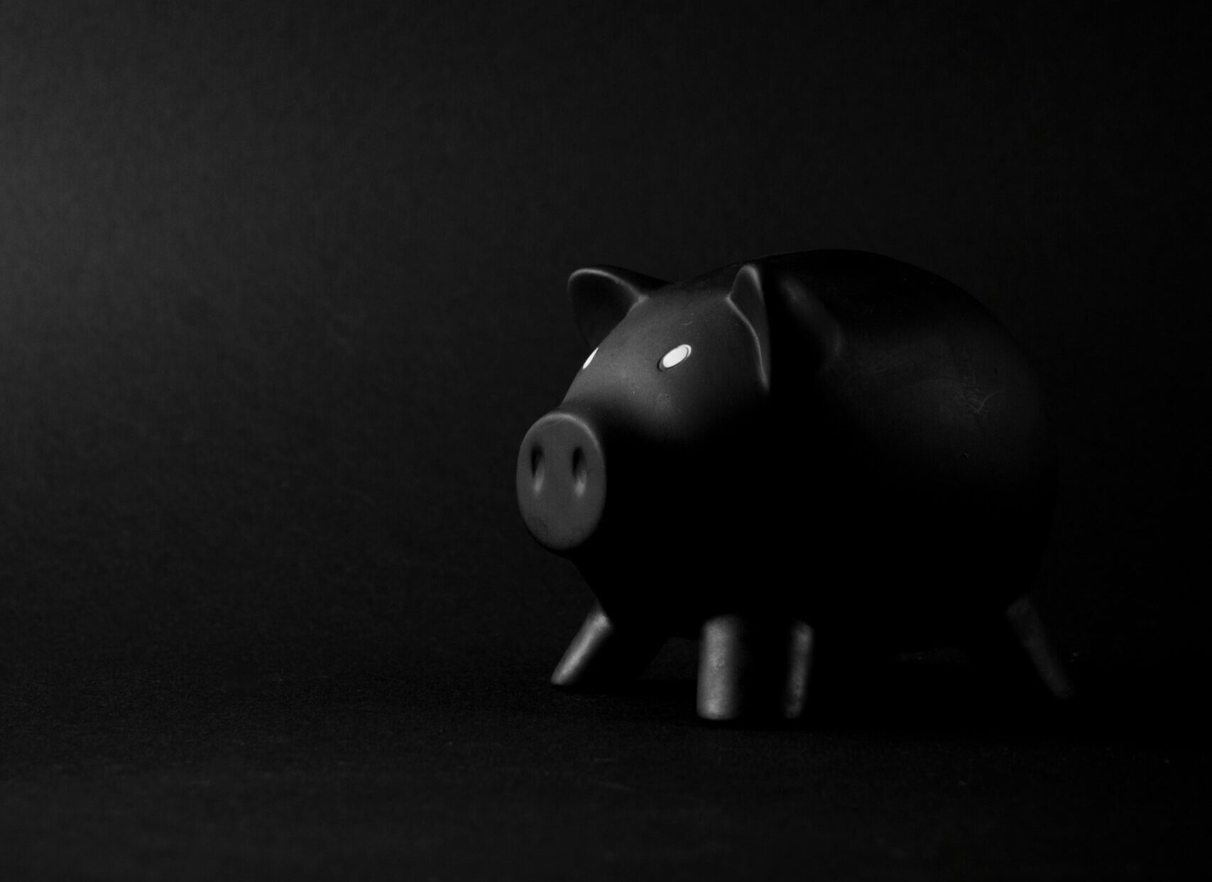 Black piggy bank against a dark background