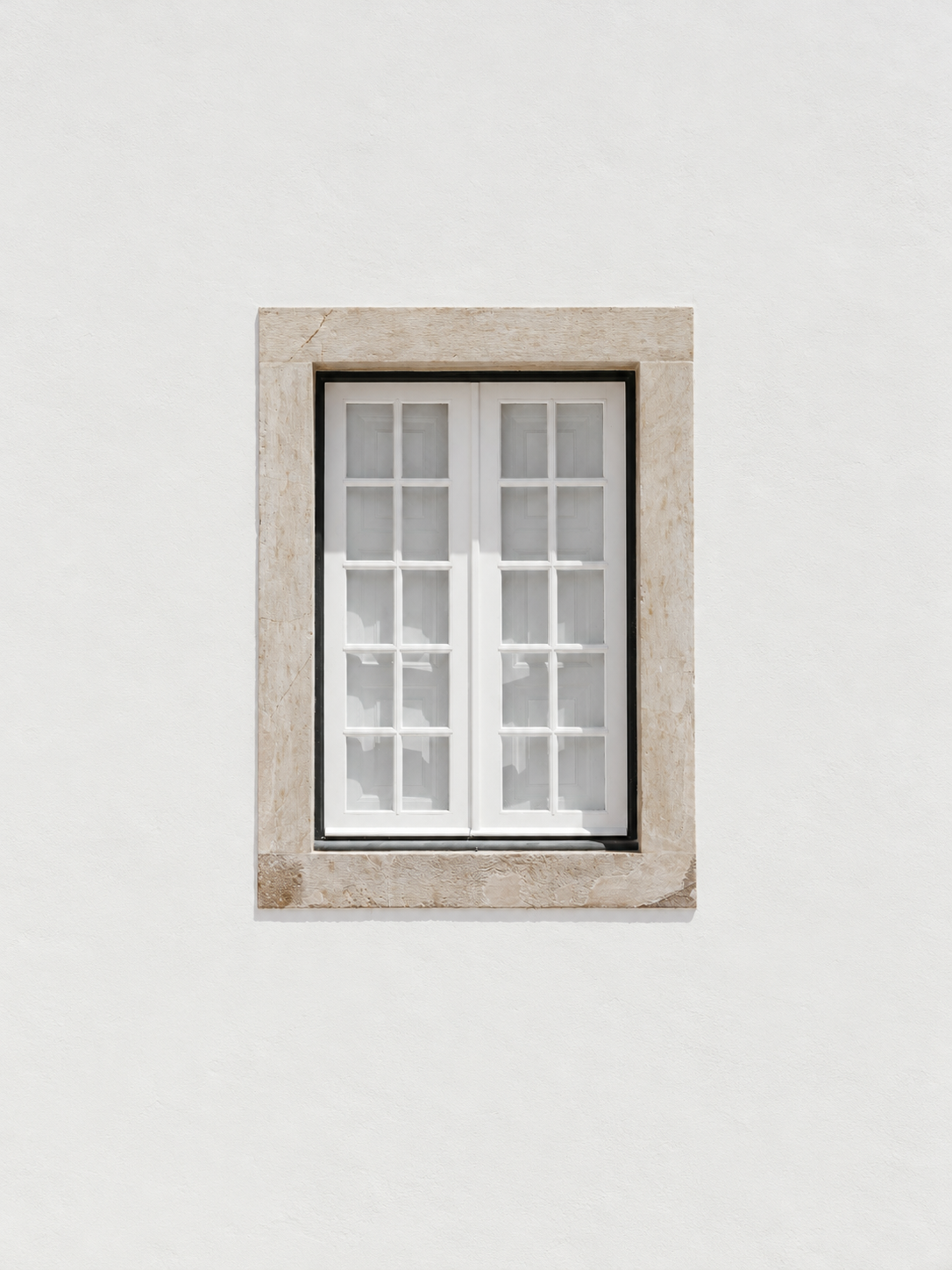 Minimalist window framed by pale stone on a light wall