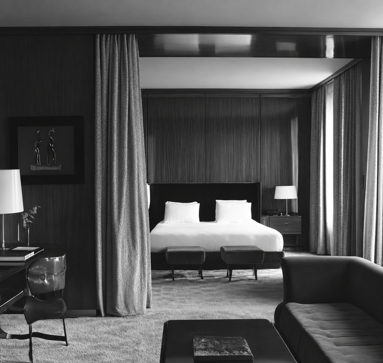 Black and white hotel suite with a bed framed by curtains